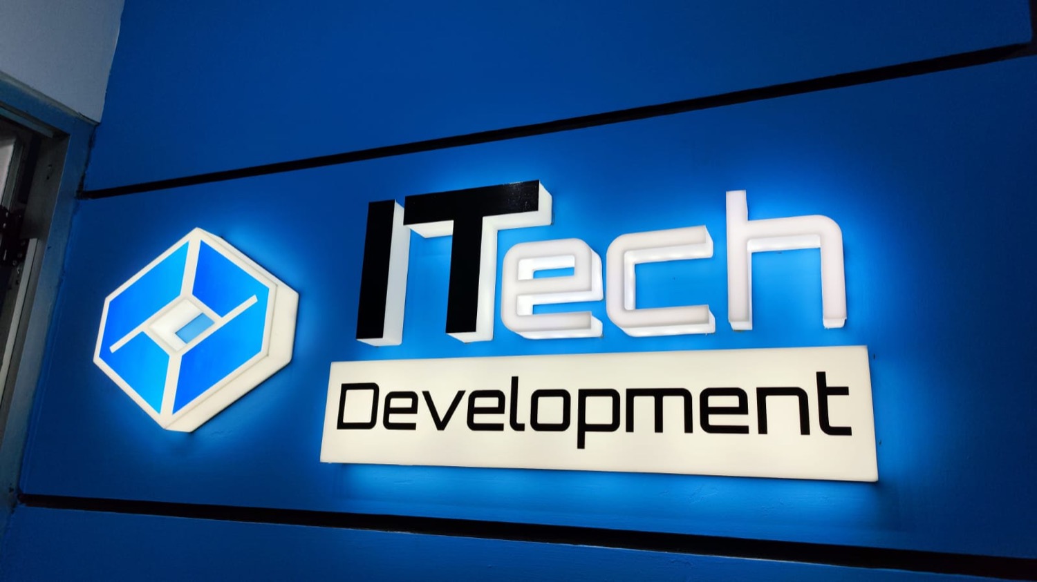 Letrero iluminado de iTech Development en la oficina